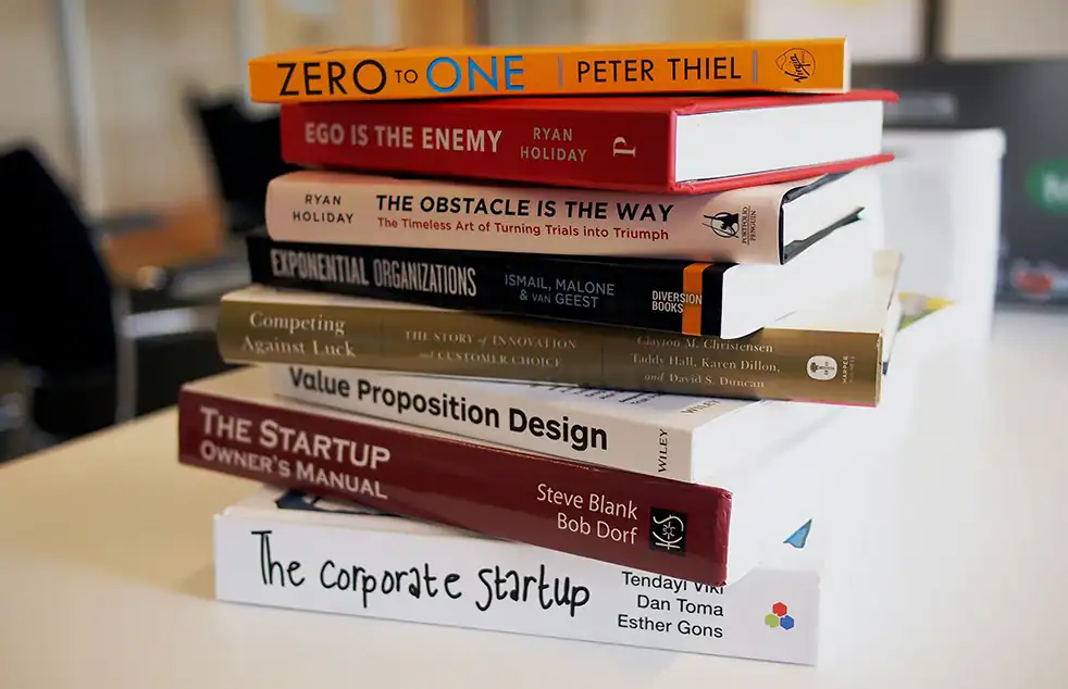 Stapel aus Gründer- und Businessbüchern auf weißem Tisch im Büro.