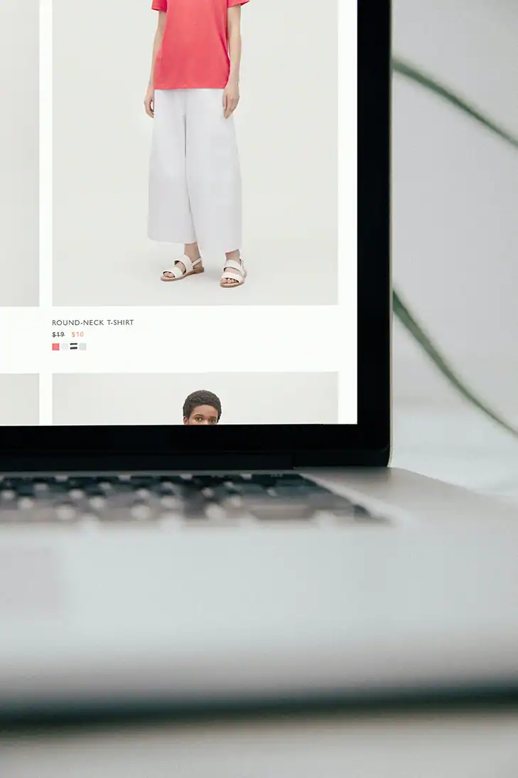Laptopbildschirm zeigt Online-Shop mit Produktfoto eines roten T-Shirts.