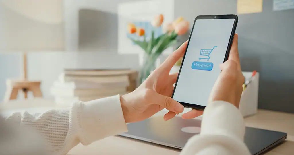 Person hält Smartphone mit Payment-Button im Onlineshop.
